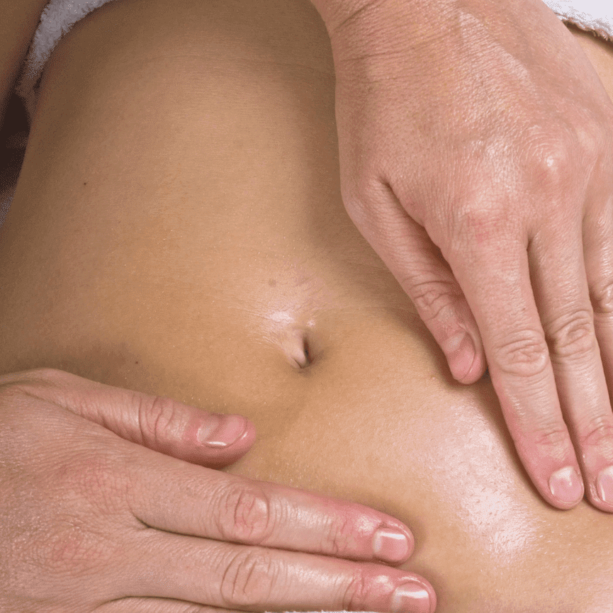 A close-up of Deandra's hands working on a client's belly to support fertility.