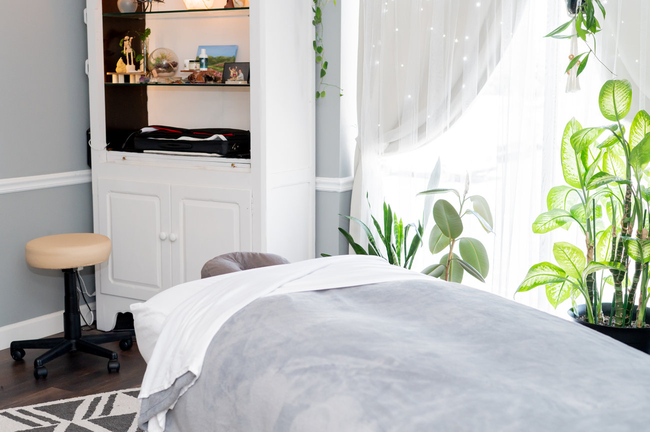 A photo of Deandra's treatment room. Light colors and fresh plants, clean space.