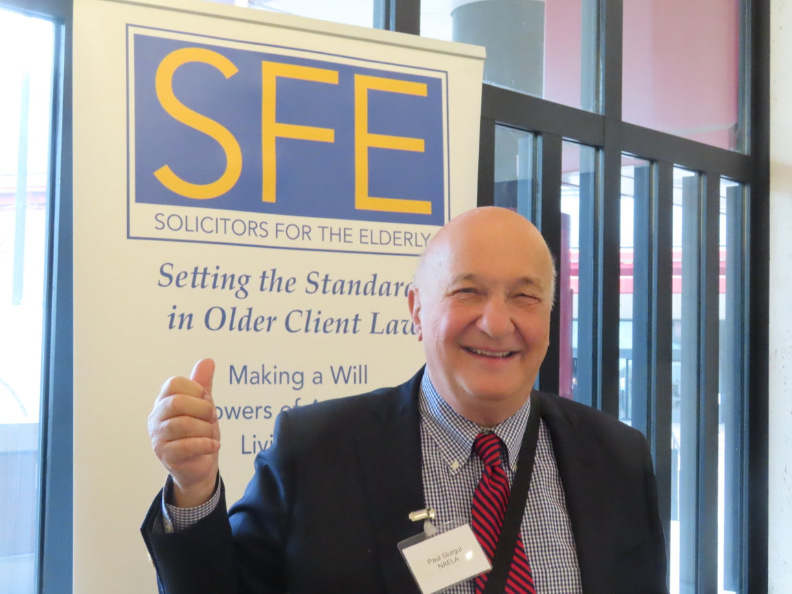 Smiling man in suit giving a thumbs-up beside an SFE Solicitors for the Elderly banner.